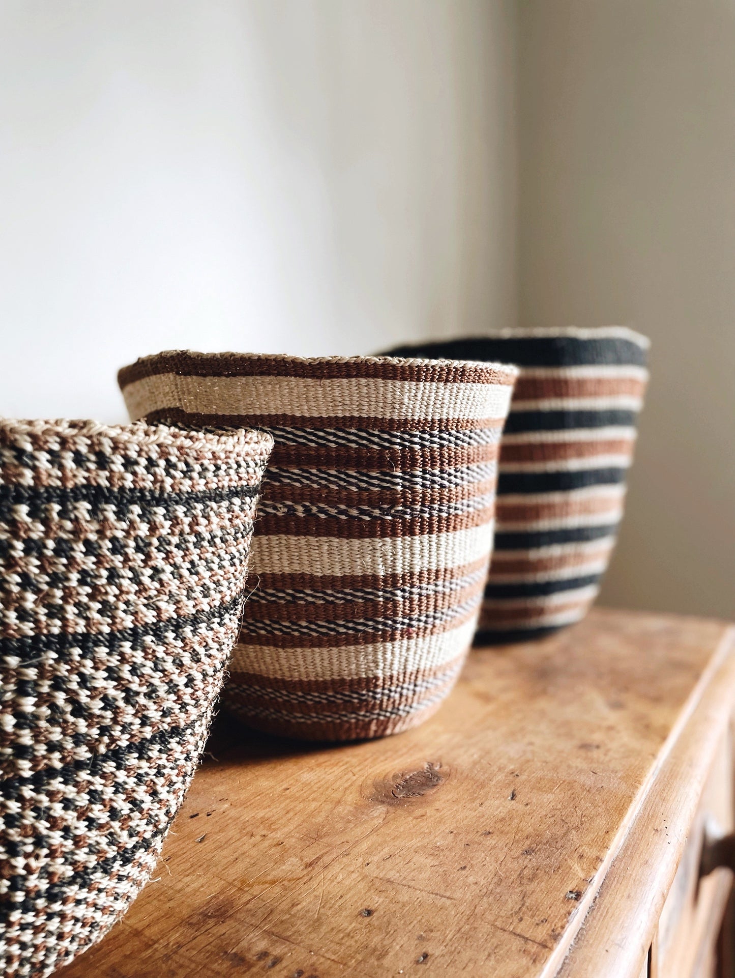 Group of three handwoven sisal baskets on chest of drawers - lifestyle.