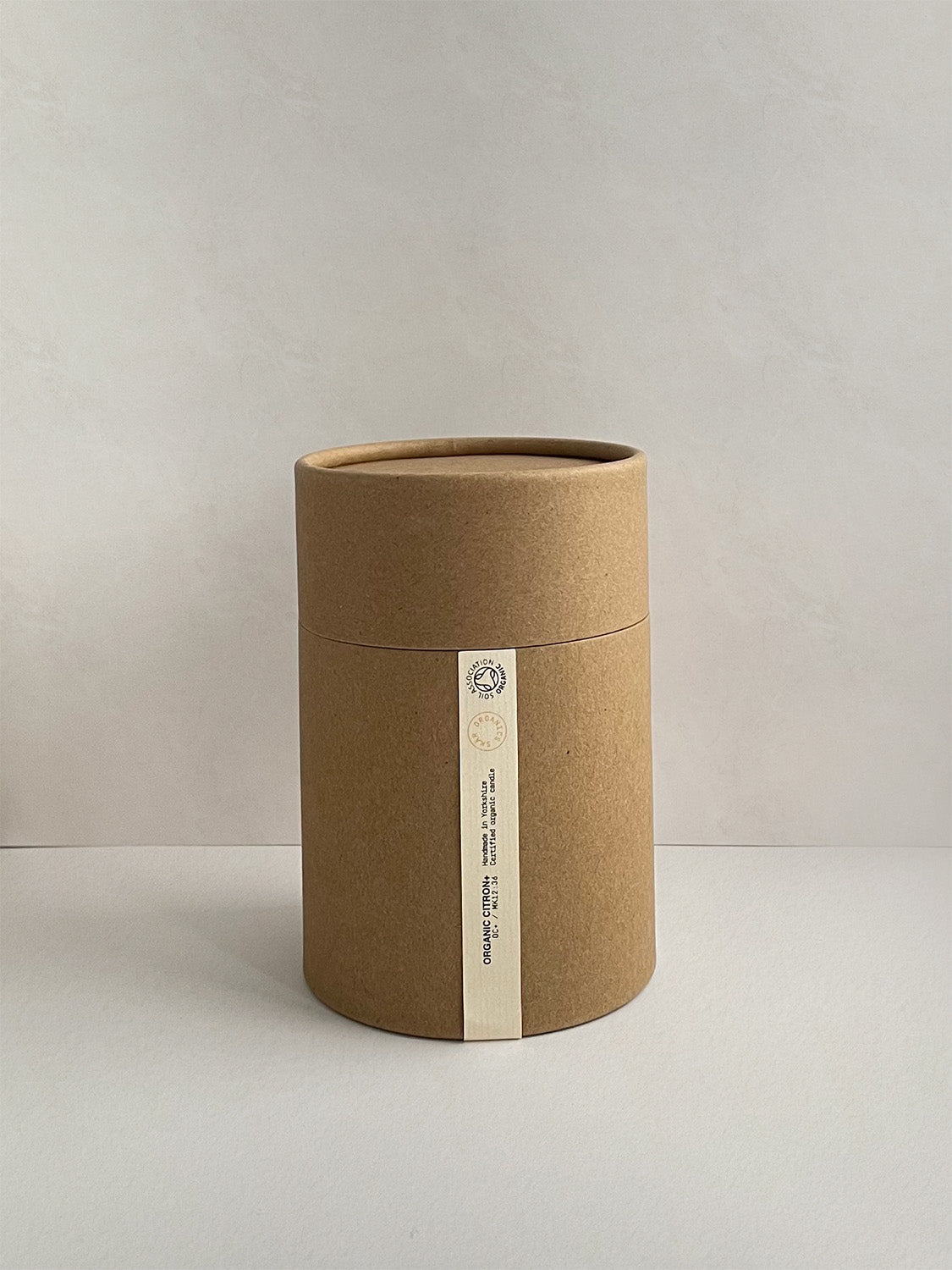 Brown cardboard tube with a label on a light grey background.