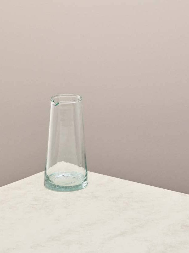 Clear glass jug on a light surface with a beige background.