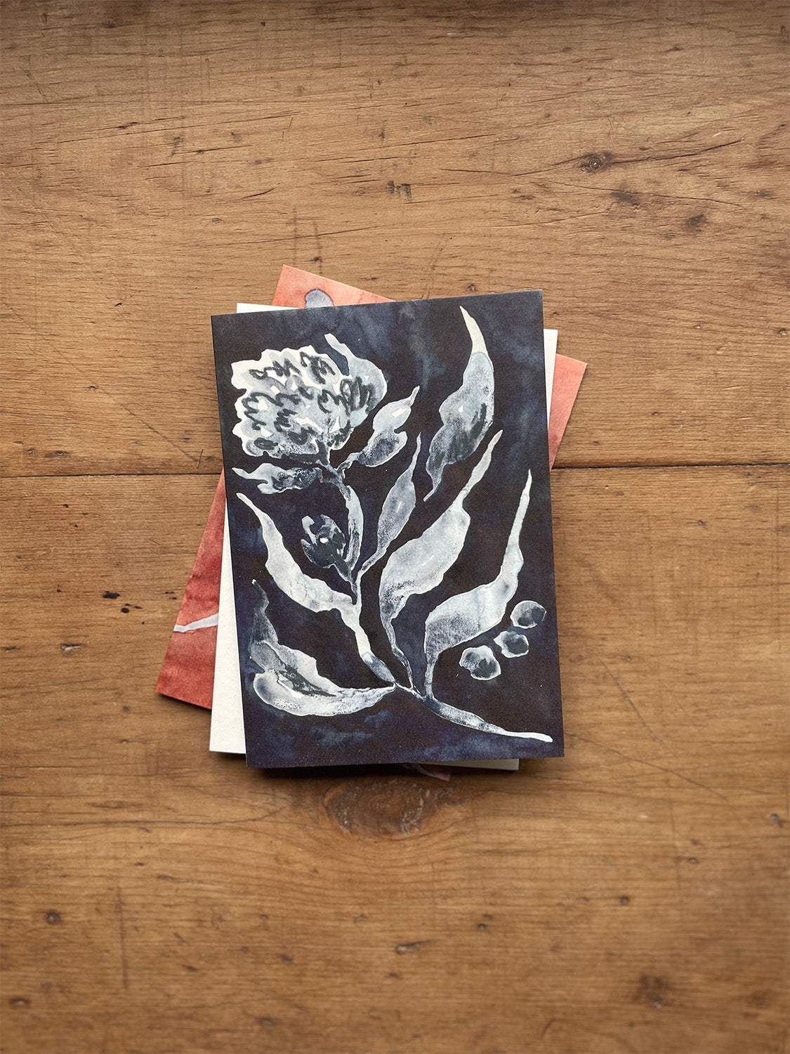 Stack of greetings cards with floral designs on a wooden surface.