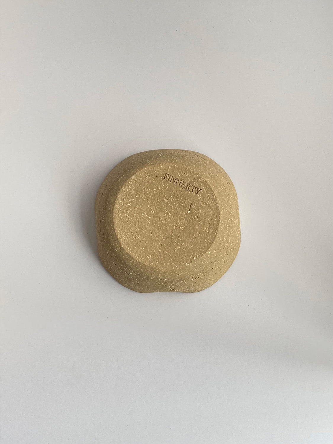 A hand-thrown ceramic candle holder in a rustic clay on a neutral background - base view.