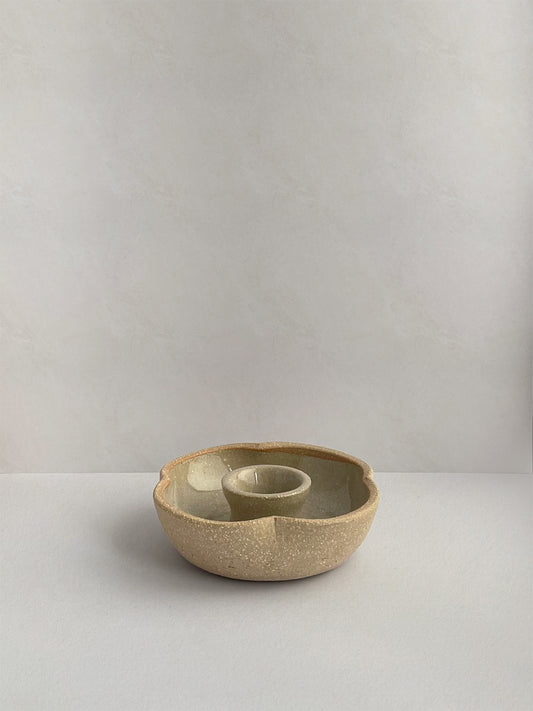 A hand-thrown ceramic candle holder in a rustic natural glaze on a neutral background - front view.