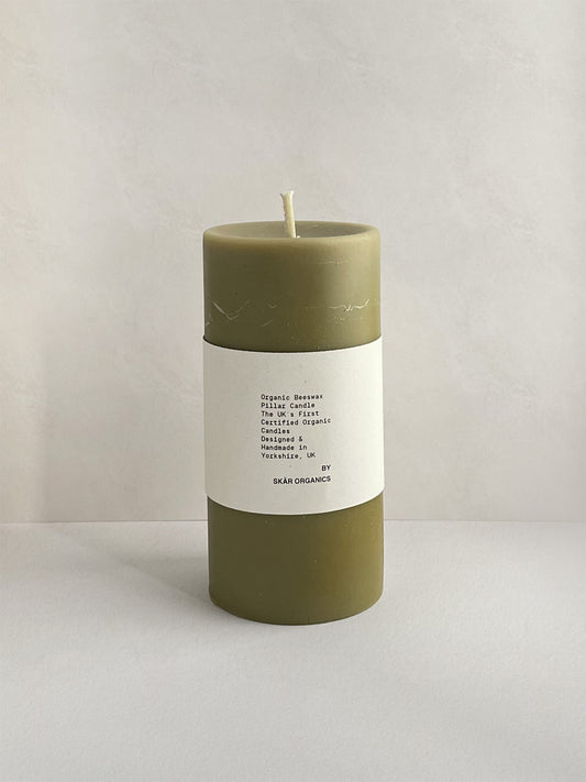 Organic beeswax & green tea pillar candle with label on a neutral background - front view.