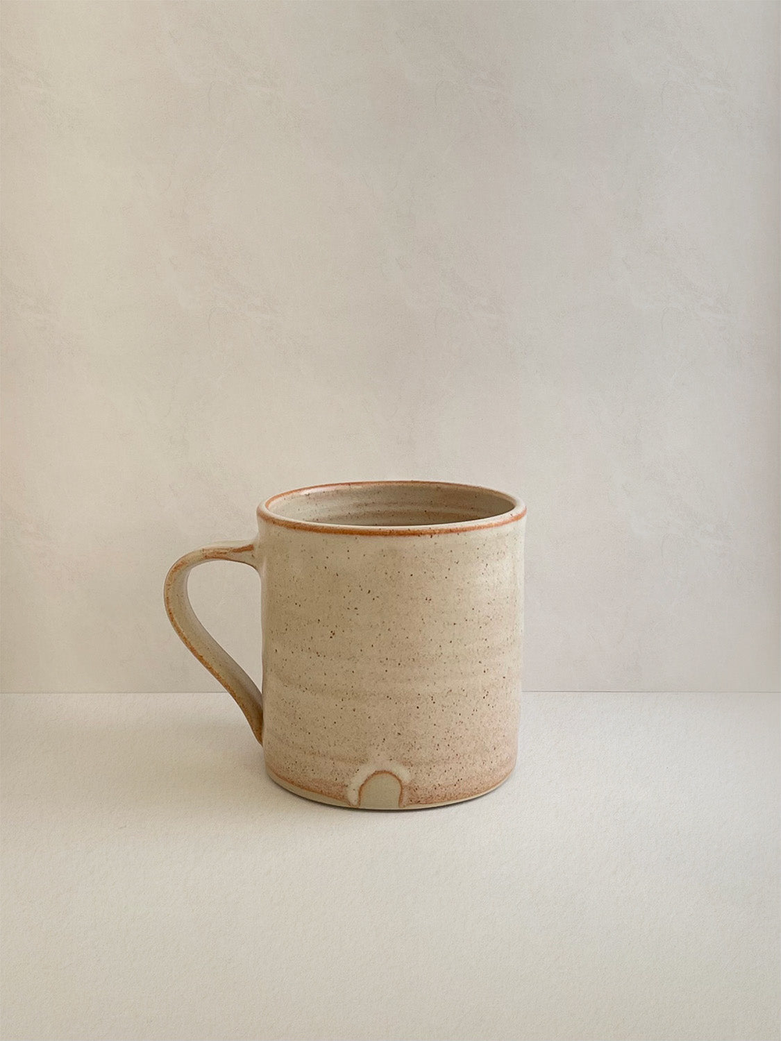 Rust ceramic mug on a neutral background - right side view.