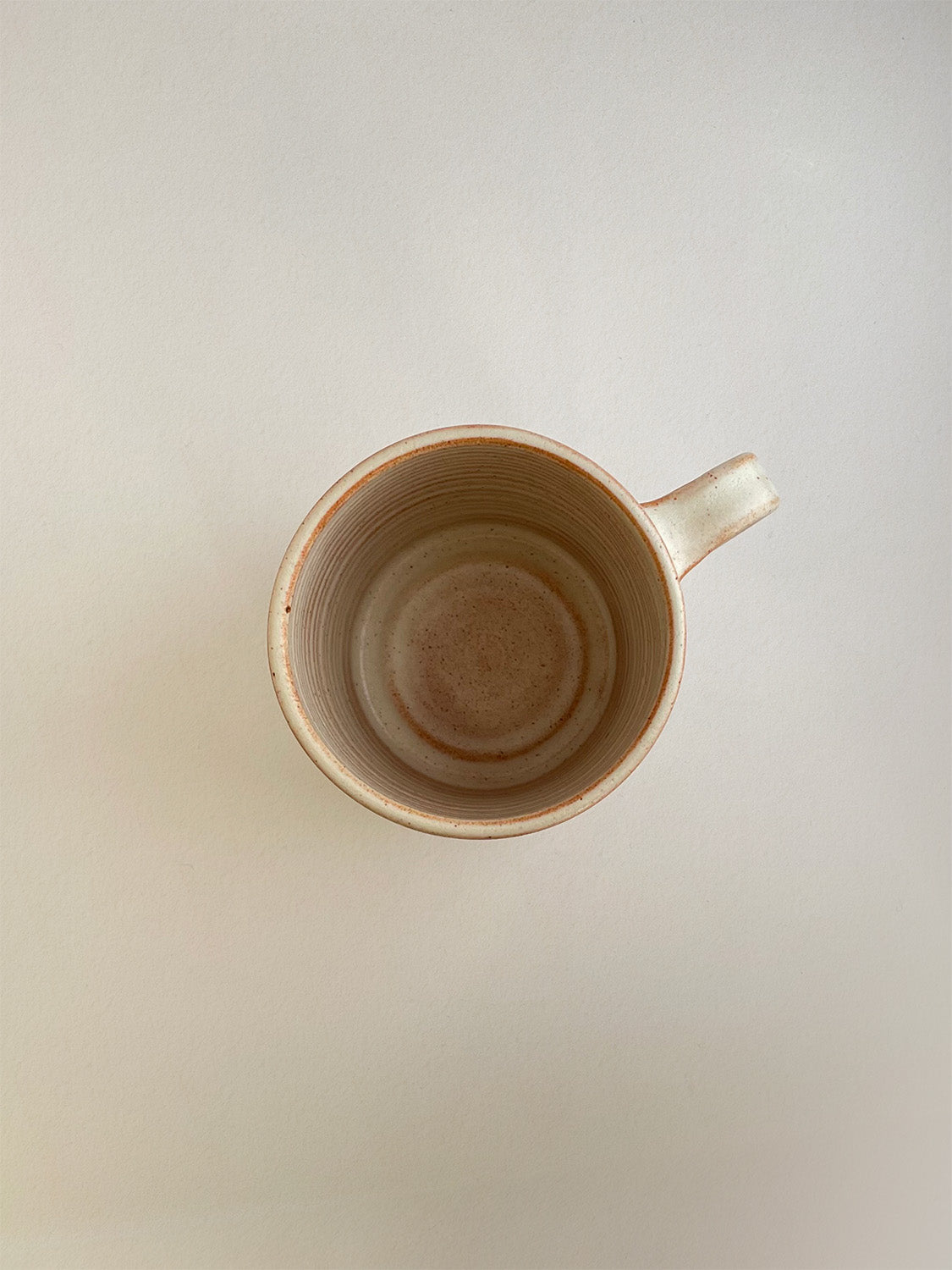 Rust ceramic mug on a neutral background - top view.