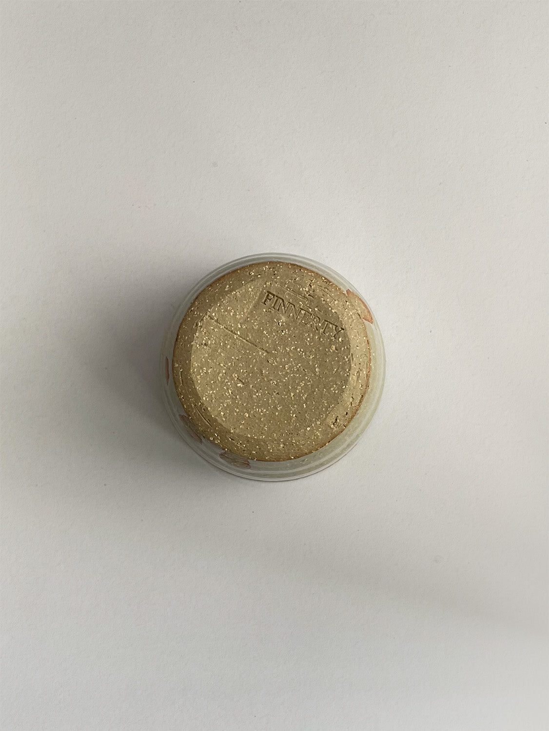 A handmade ceramic coffee cup with a rustic glaze finish, showing speckling and unique finger marks from the making process - base view.