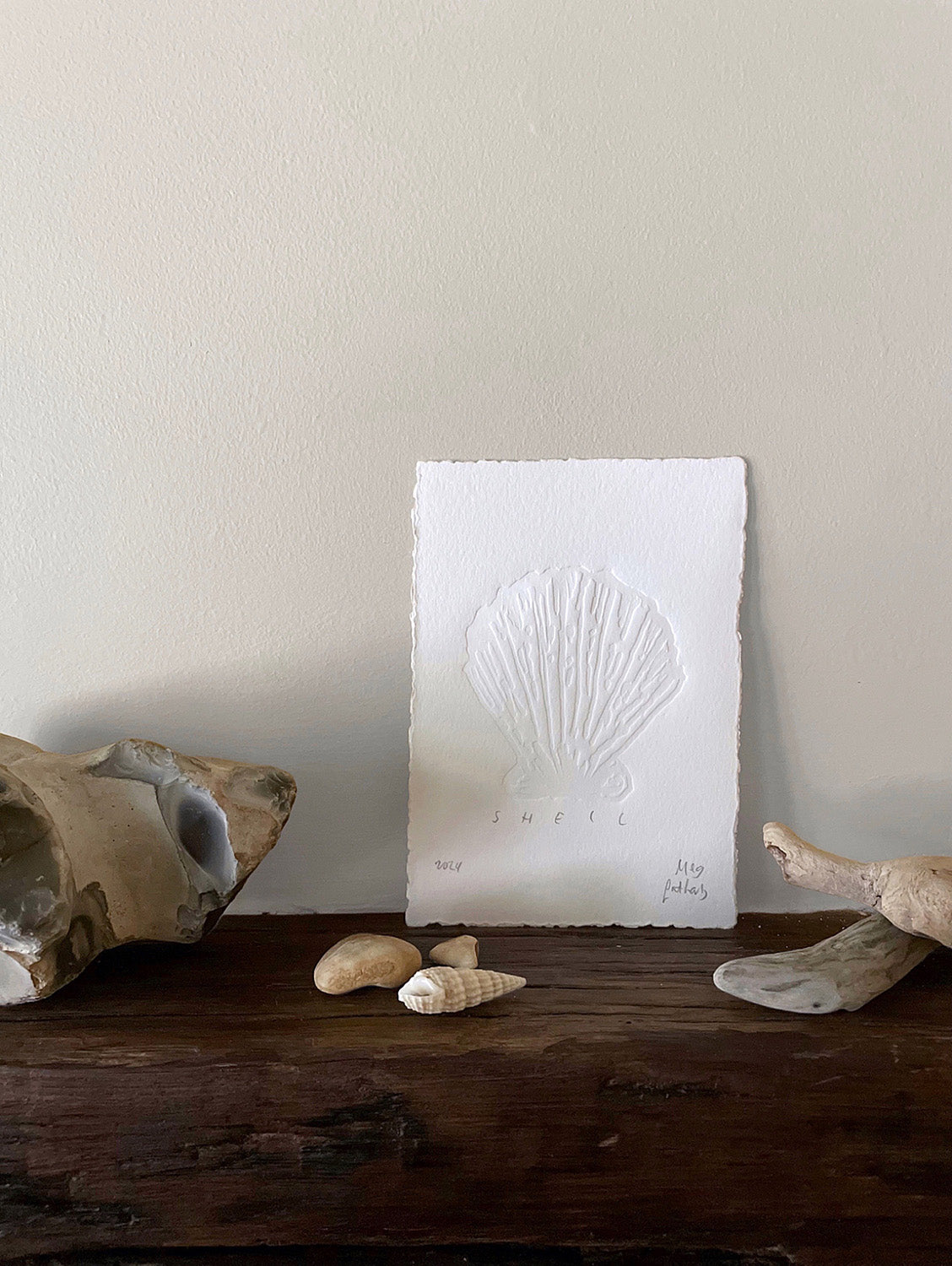 Shell hand-embossed artwork with rock, shells and driftwood.