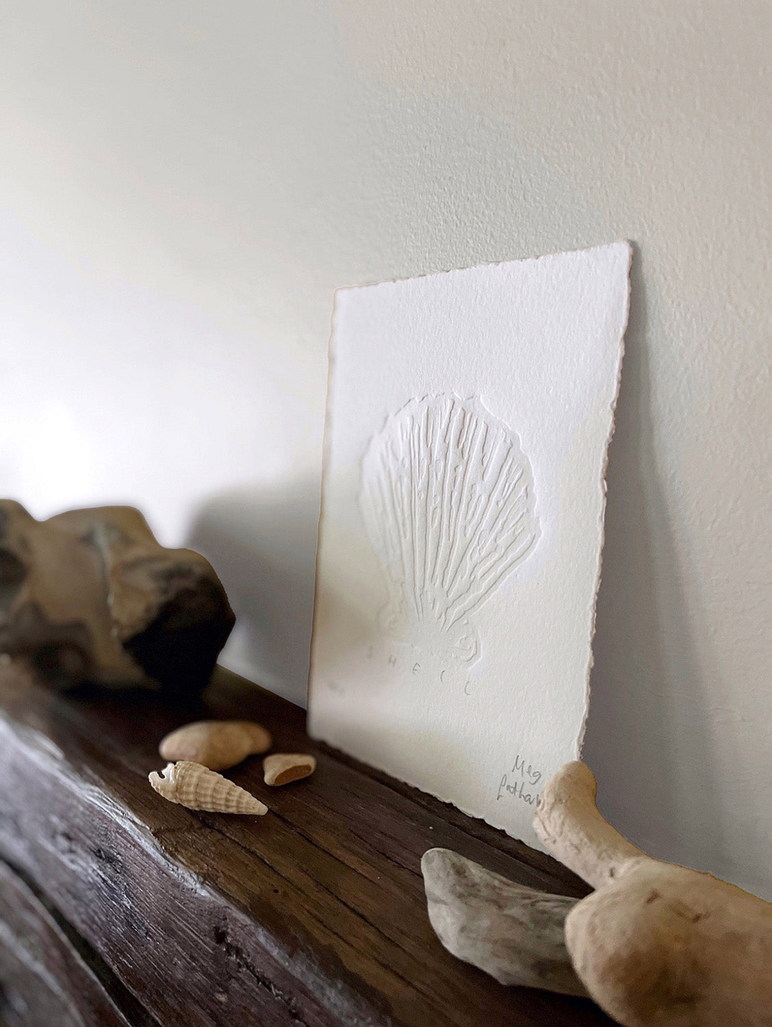 Shell hand-embossed artwork with rock, shells and driftwood.