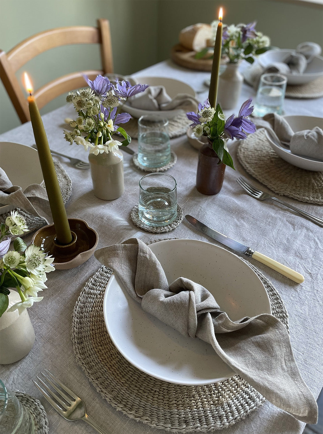 Elegant dining table setting with candles, flowers, and place settings.