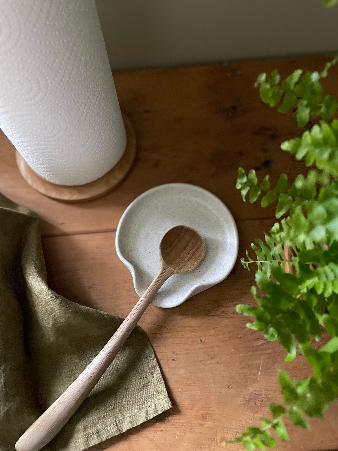 Handmade ceramic tableware in rustic tones with playful, organic patterns on a wooden surface.