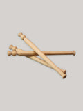 Three beech wood porridge spurtles stacked on a neutral background.