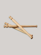 Three beech wood porridge spurtles stacked on a neutral background.