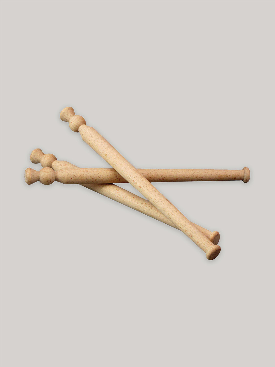 Three beech wood porridge spurtles stacked on a neutral background.