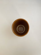 Burnt orange ceramic cup on a neutral background - top view.