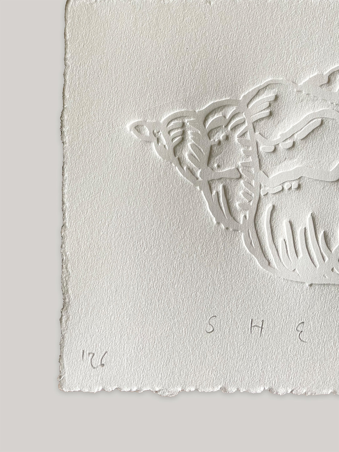 Conch shell hand-embossed artwork on white paper with 'Shell' text and deckled edges - close-up detail 1.