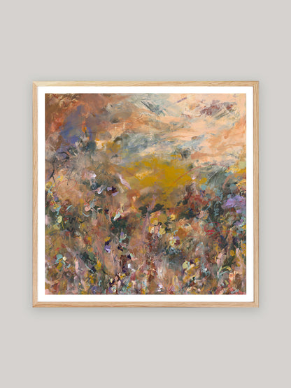 Abstract art print with warm colours in oak frame on a neutral background.