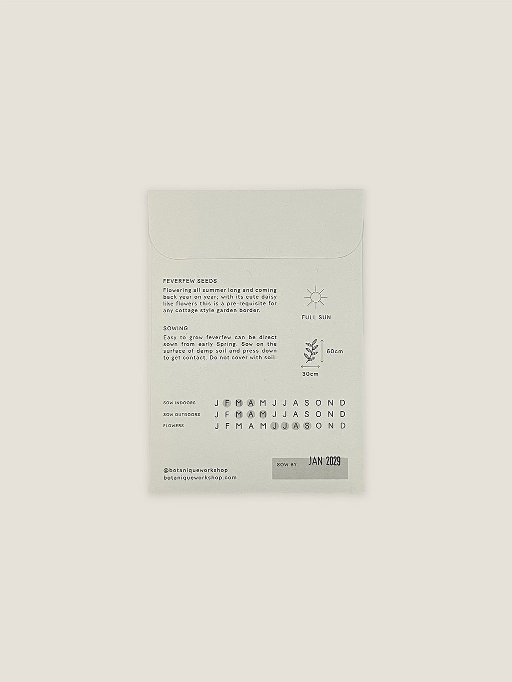 Back of Feverfew seed packet with text and growing instructions on a neutral background.