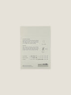 Back of Feverfew seed packet with text and growing instructions on a neutral background.