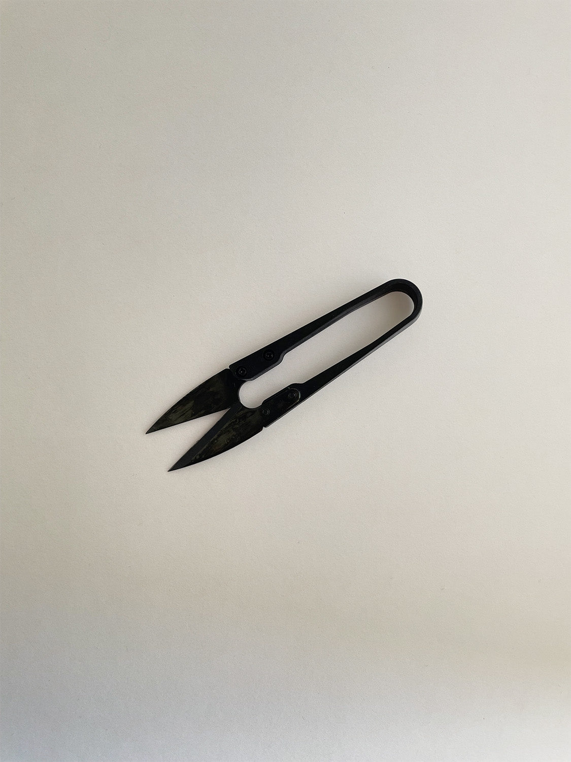 A pair of black metal pruning snips with a spring-loaded design, on a neutral background.