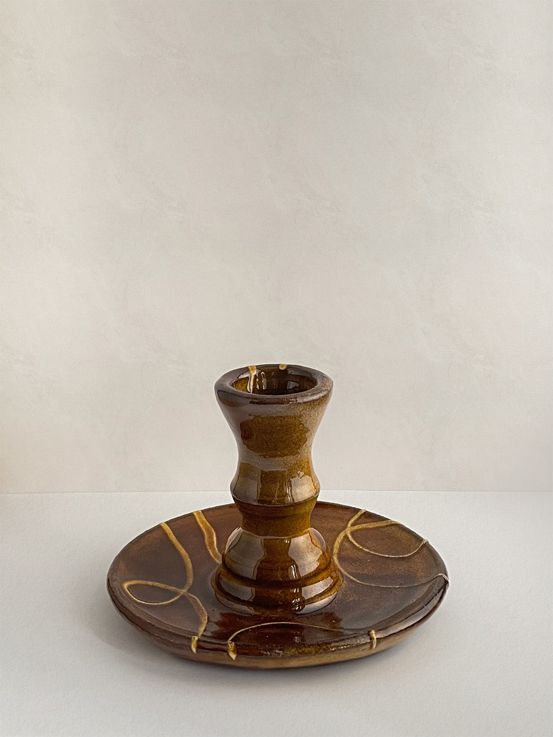 Brown and gold handmade ceramic candle holder with decorative patterns on a neutral background - back view.