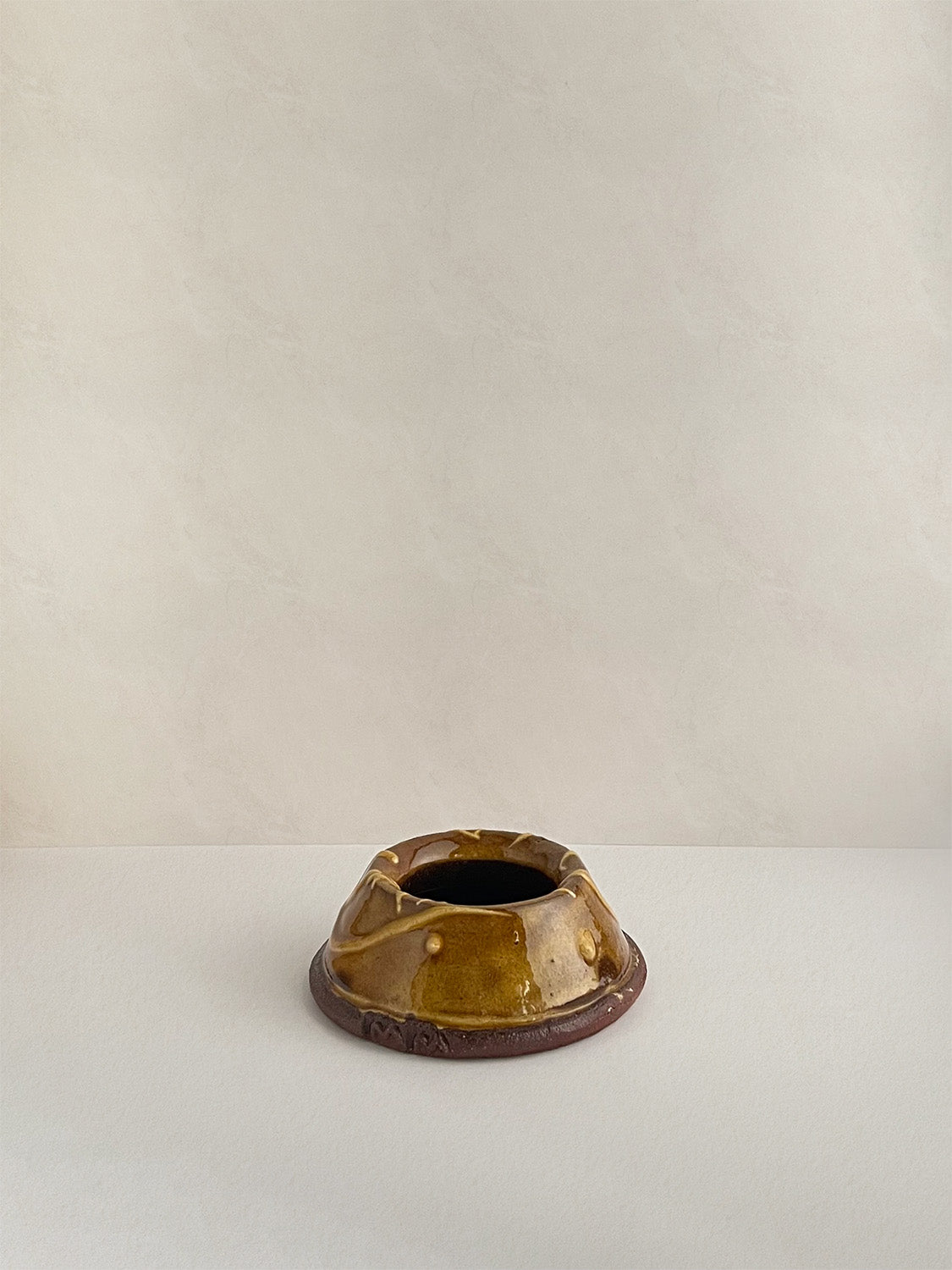 Brown and gold handmade ceramic egg cup on a neutral background - back view.