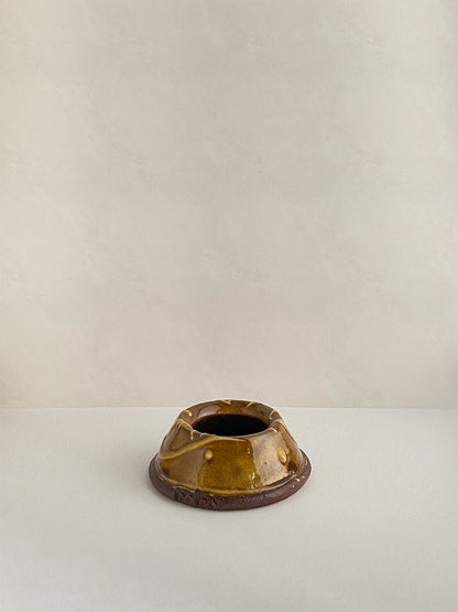 Brown and gold handmade ceramic egg cup on a neutral background - back view.