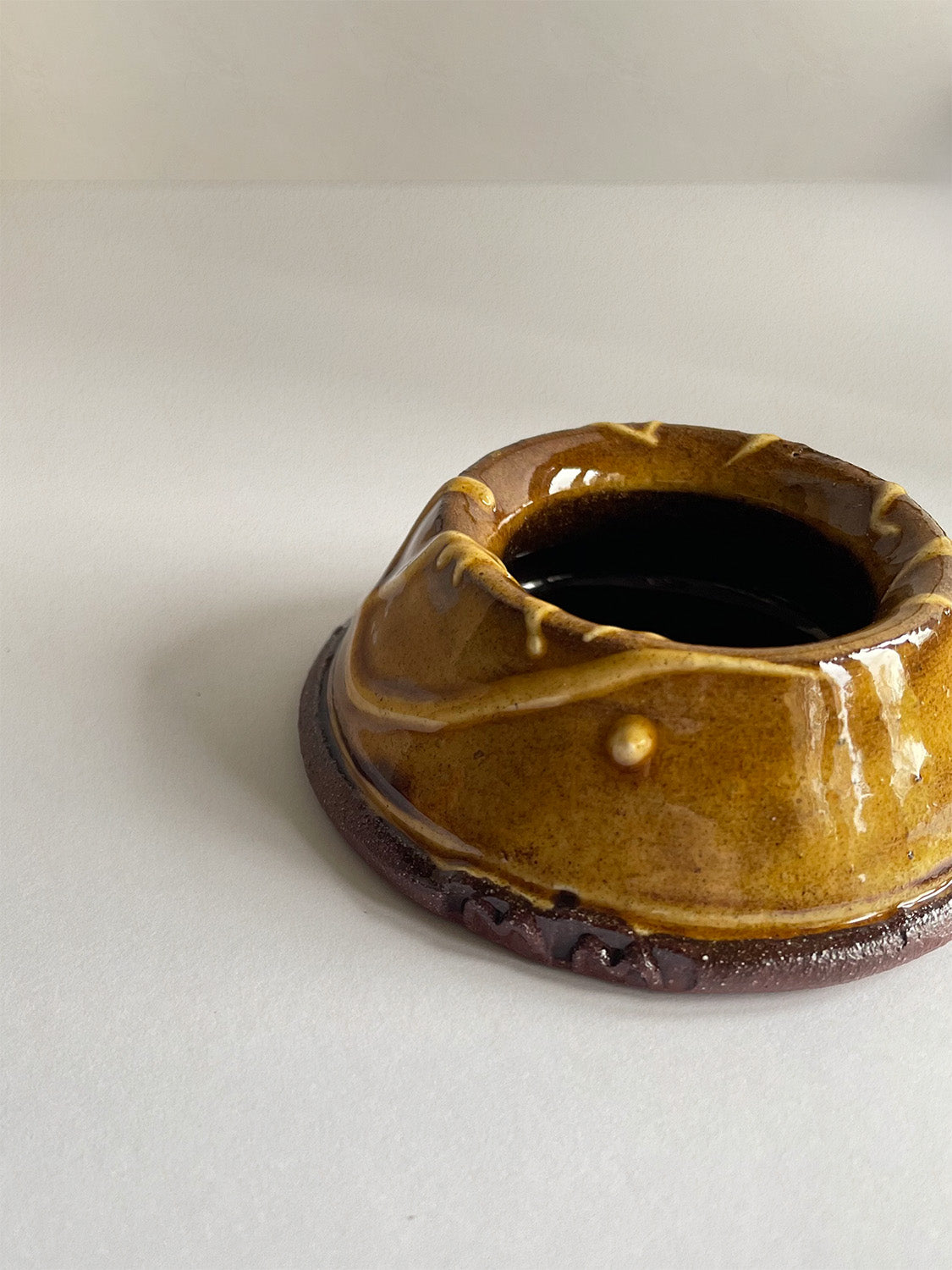 Close-up of brown and gold handmade ceramic egg cup on a neutral background.