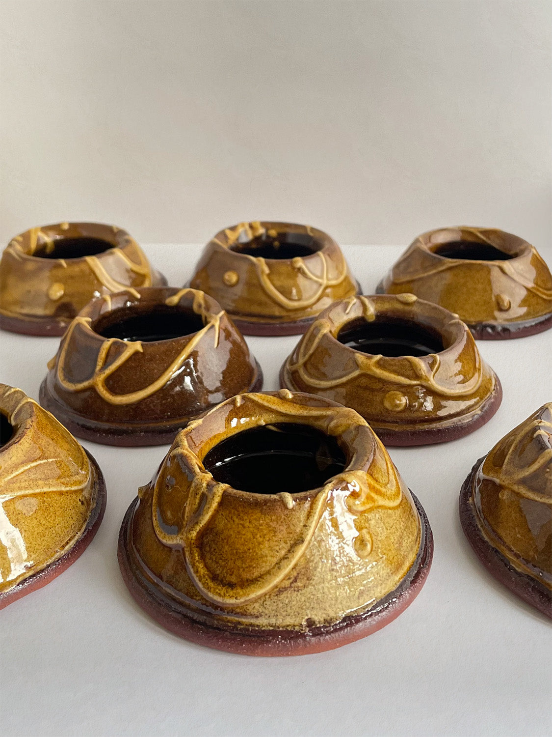Set of brown and gold handmade ceramic egg cups on a neutral background.
