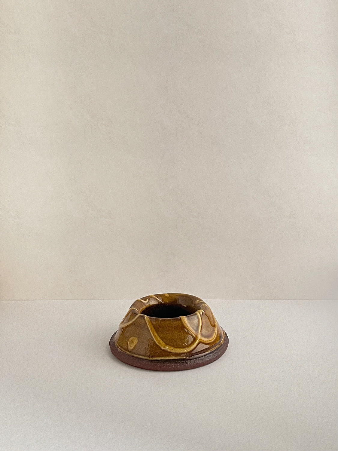 Brown and gold handmade ceramic egg cup on a neutral background - front view.
