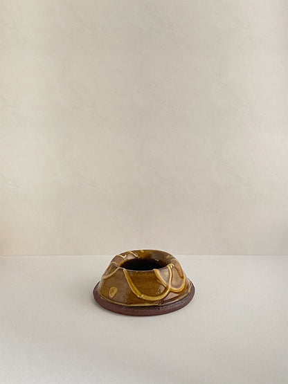 Brown and gold handmade ceramic egg cup on a neutral background - front view.