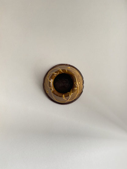 Brown and gold handmade ceramic egg cup on a neutral background - top view.