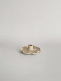 A handmade ceramic candle holder with a softly frilled base and a central cylindrical stem, on a neutral background.