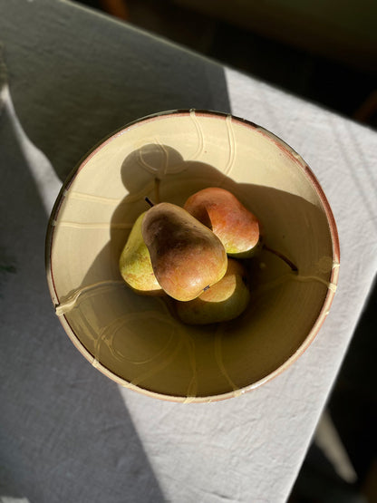 Ceramic serving bowl with pears on a linen tablecloth.
