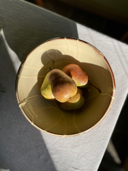 Ceramic serving bowl with pears on a linen tablecloth.