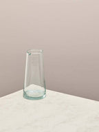 Clear glass jug on a light surface with a beige background.