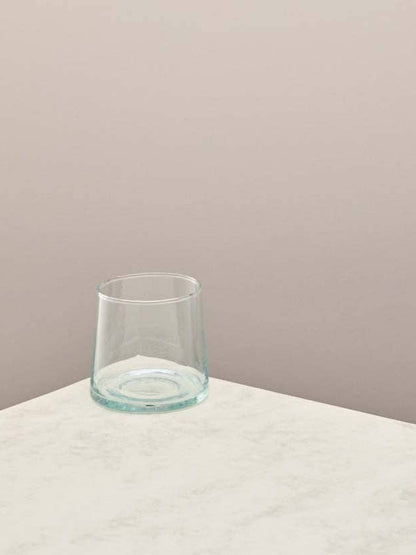 Clear glass low tumbler on a light surface with a beige background.