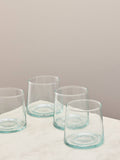 A set of four clear handmade recycled low tumblers on a light surface.