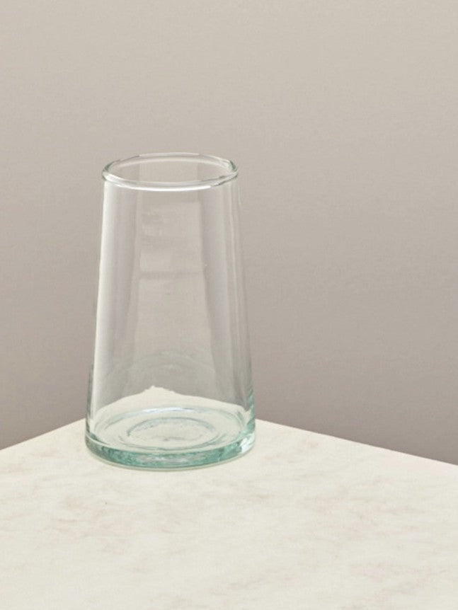 A single handmade recycled tall glass on a light surface.