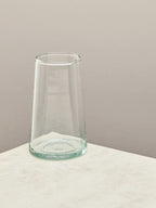 A single handmade recycled tall glass on a light surface.