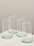 A set of four handmade recycled tall glasses on a light surface.