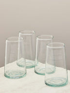 A set of four handmade recycled tall glasses on a light surface.