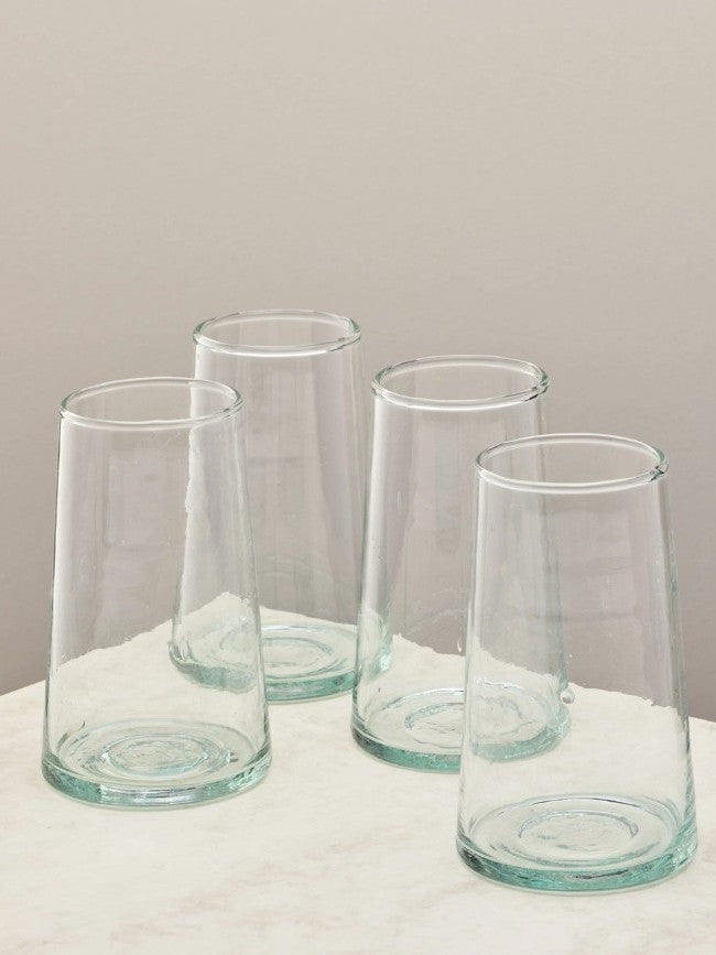 A set of four handmade recycled tall glasses on a light surface.