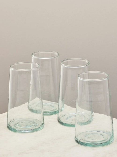 A set of four handmade recycled tall glasses on a light surface.