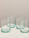 A set of four clear handmade recycled tumblers on a light surface.