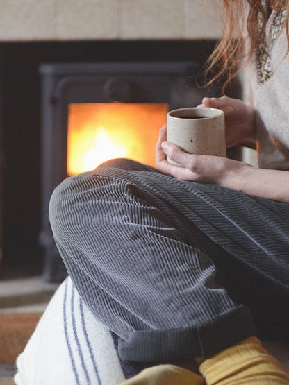 Person holding mug of hot chocolate by the fire.