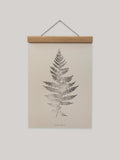 Framed print of a fern leaf on a beige background.