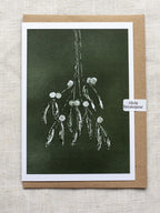 Botanical Christmas card with mistletoe design on a dark green background, with a Kraft paper envelope and 'Alicia Breakspear' sticker seal.