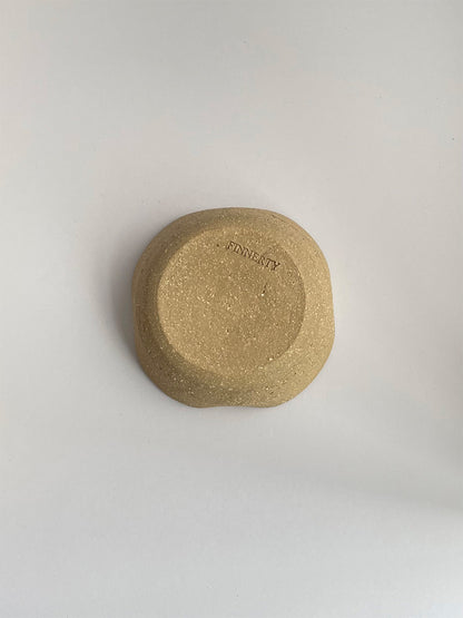 A hand-thrown ceramic candle holder in a rustic clay on a neutral background - base view.