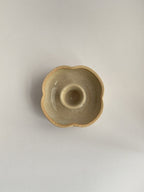 A hand-thrown ceramic candle holder in a rustic natural glaze on a neutral background - top view.