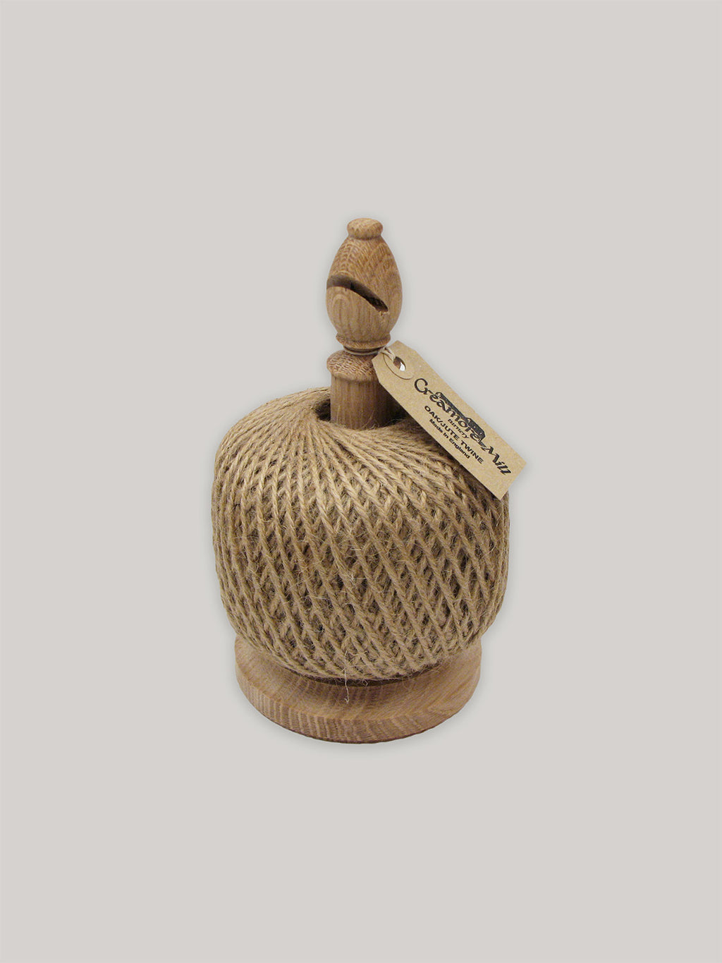 Solid oak twine holder with ball of jute twine and Kraft paper label on a neutral background.